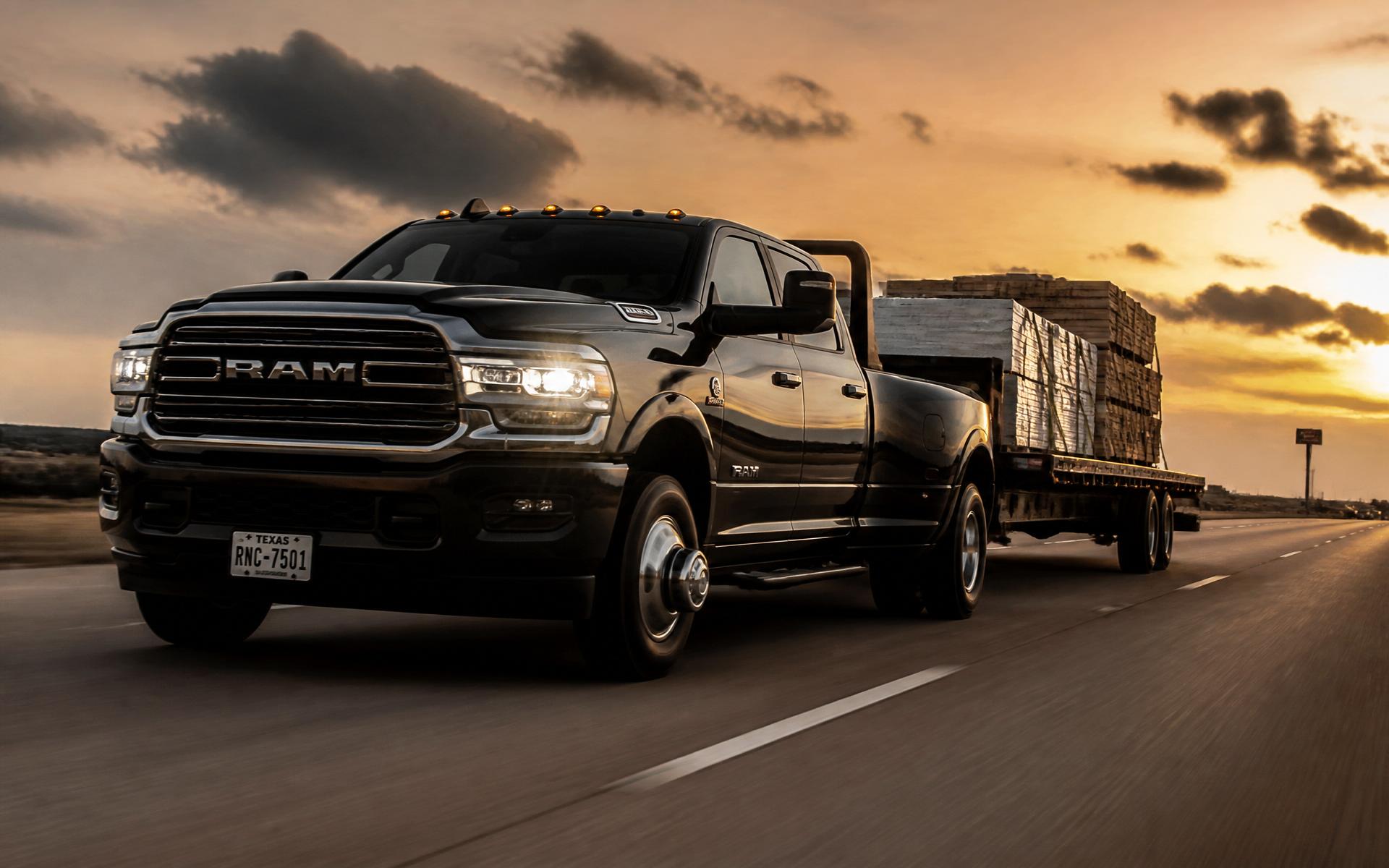 Black heavy-duty hot shot truck hauling freight on a Texas highway at sunset